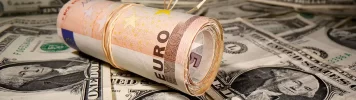 EURUSD - Rolled euro bills resting on a background of US dollars