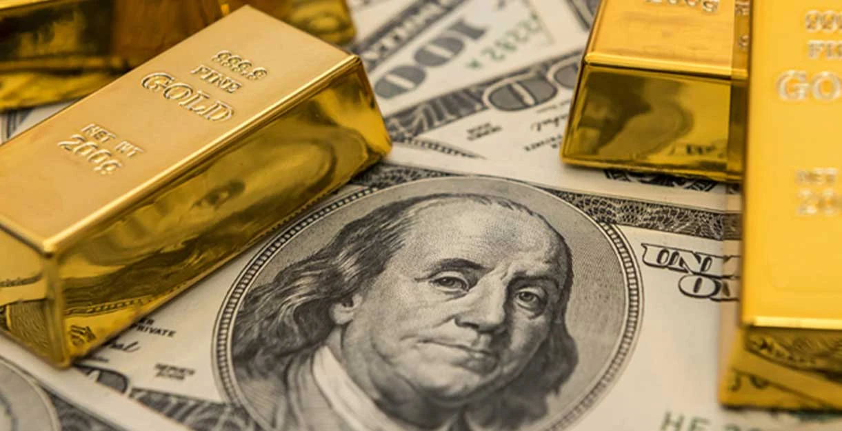Several gold bars resting on top of 100-dollar bills, prominently featuring Benjamin Franklin's portrait