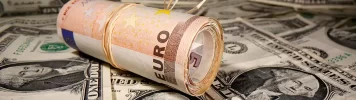 EURUSD - Rolled euro bills resting on a background of US dollars -2025